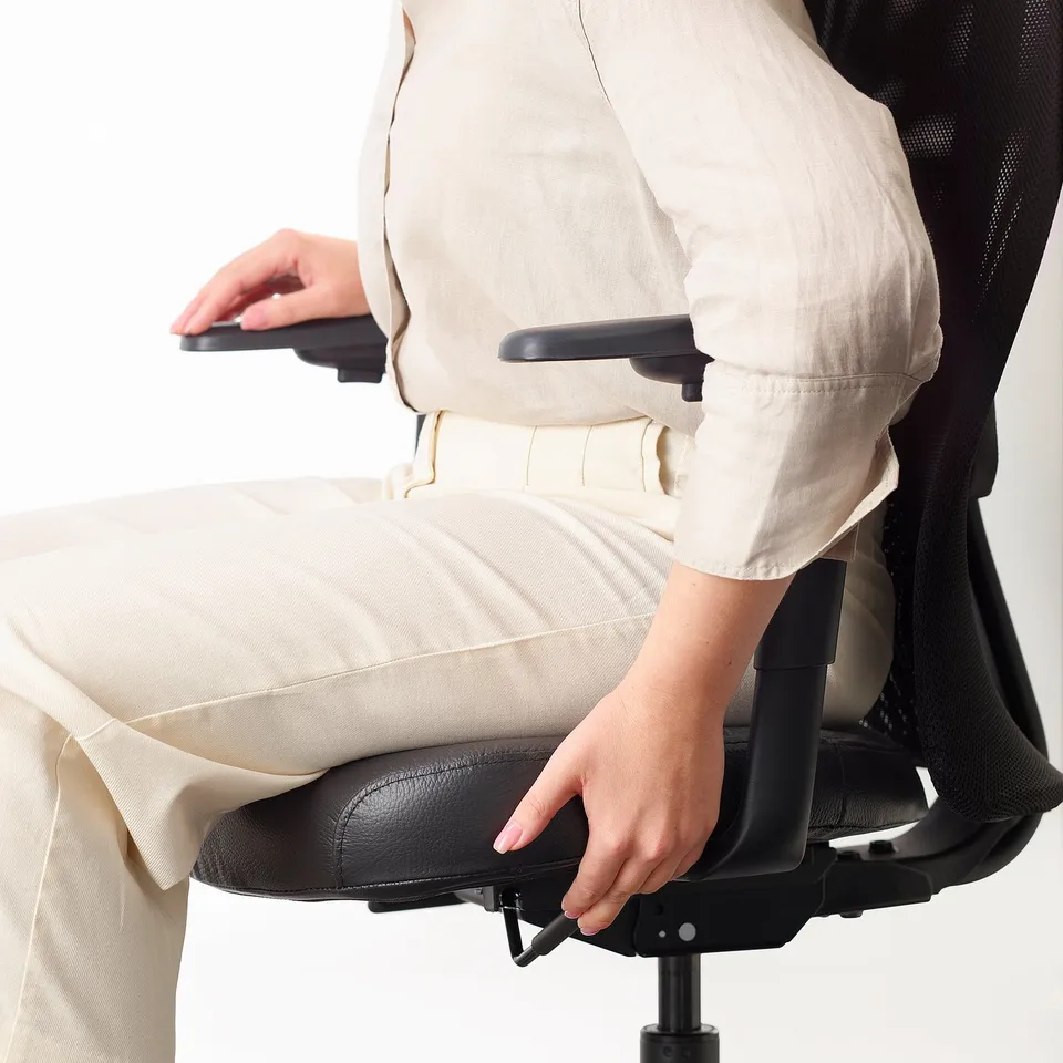 Person adjusting black lever on back of office chair.
