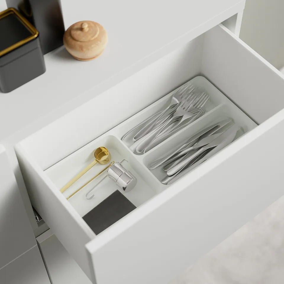 Open drawer with silverware organiser; spoons, forks, knife.
