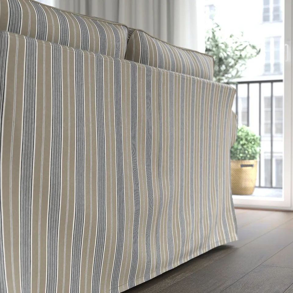 Striped sofa with thick cushions facing window, showcasing comfortable and reversible seats.