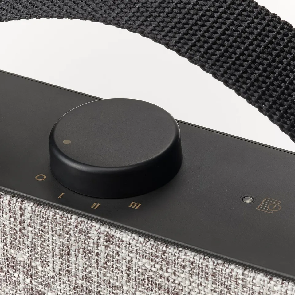 Black air purifier with control dial and strap. Modern design, durable material.