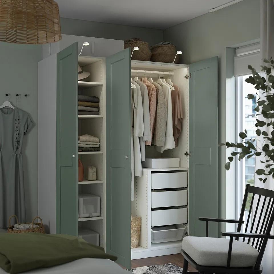 A well-organized wardrobe with green doors displays clothes, shelves, and drawers. Lighting inside reveals neatly arranged items.