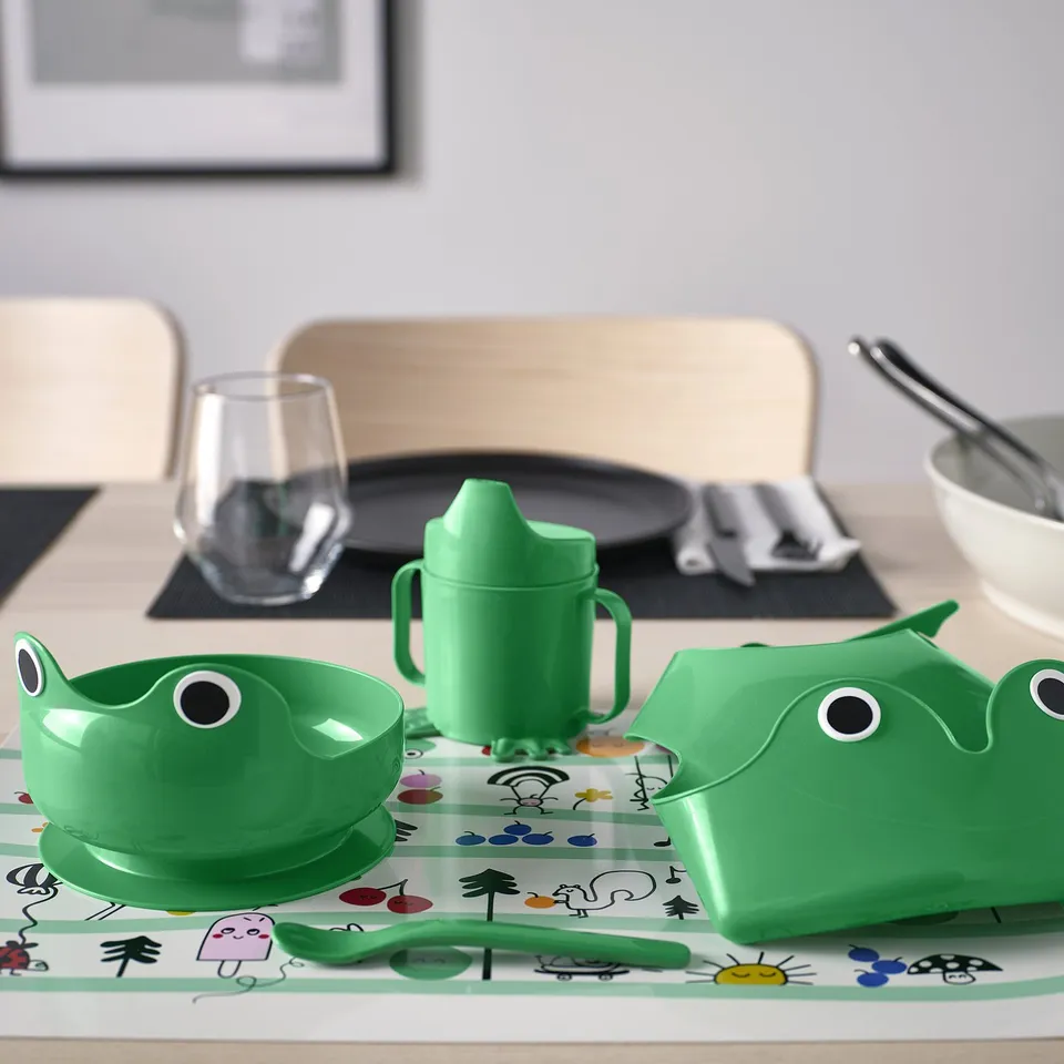 Green kids MATA set: bowl, cup, spoon, bib. Frog design, steady, bright plastic. Fits table, easy grips.