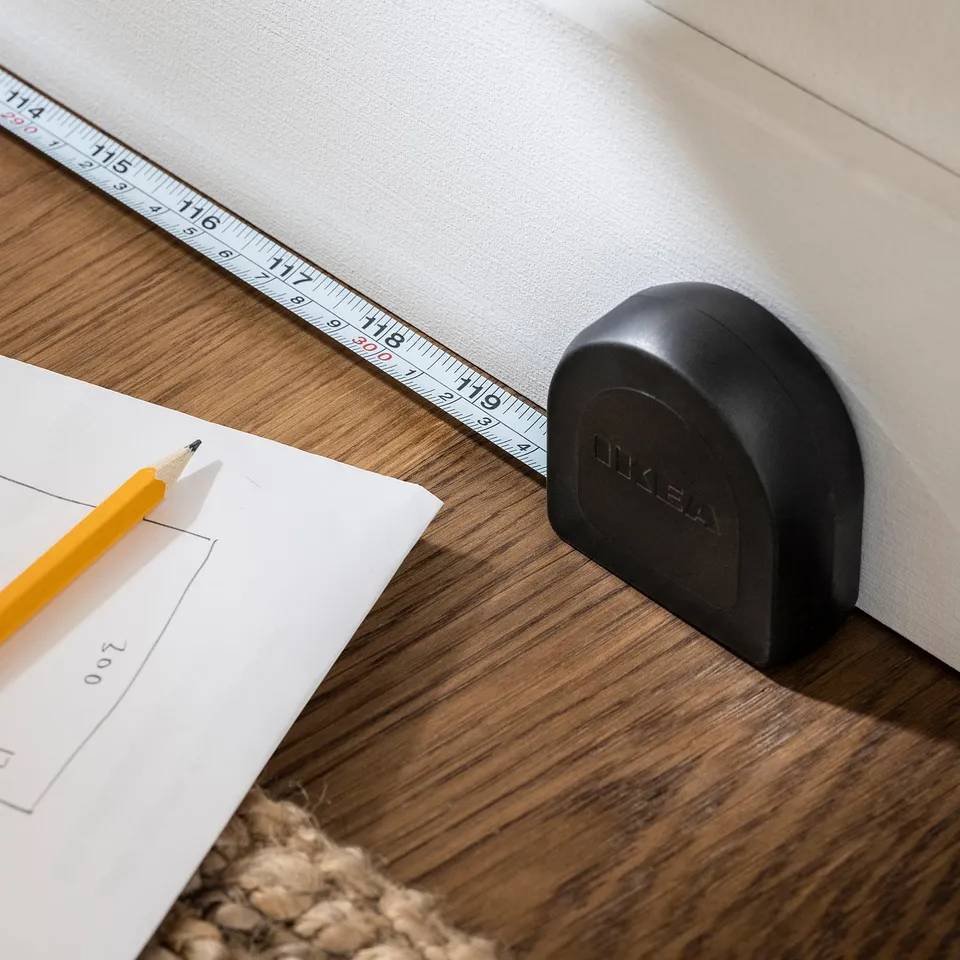 A measuring tape on a wooden surface, with a pencil and paper, showing precise measurement markings.