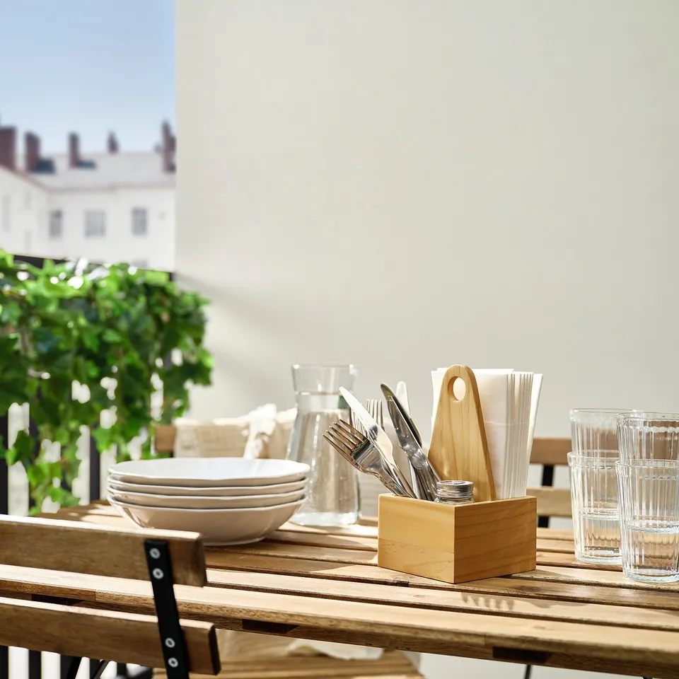 Wooden CHOKLADHAJ organiser on table with silverware and napkins, near bowls and glasses, made of solid pine, rectangular shape, natural colour.