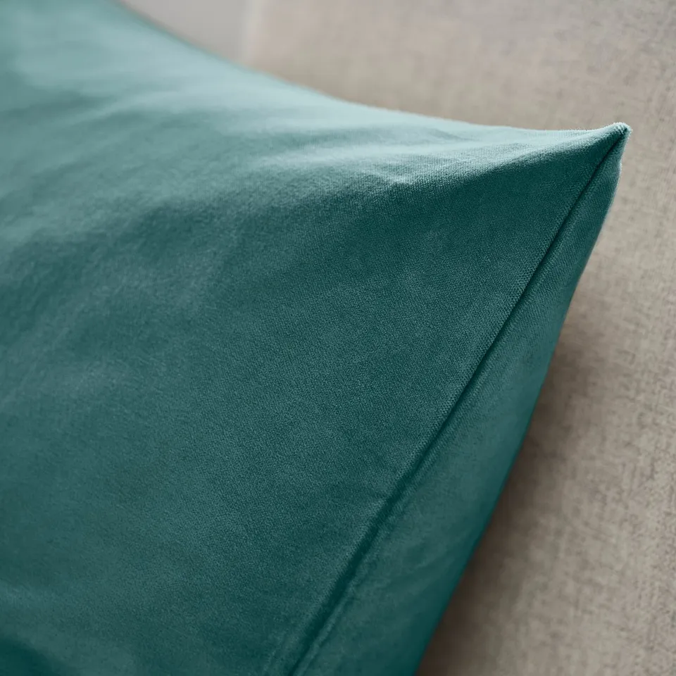 Teal cushion cover made of luxurious cotton velvet; soft, smooth texture. Close-up shows neat stitching and zip detail.