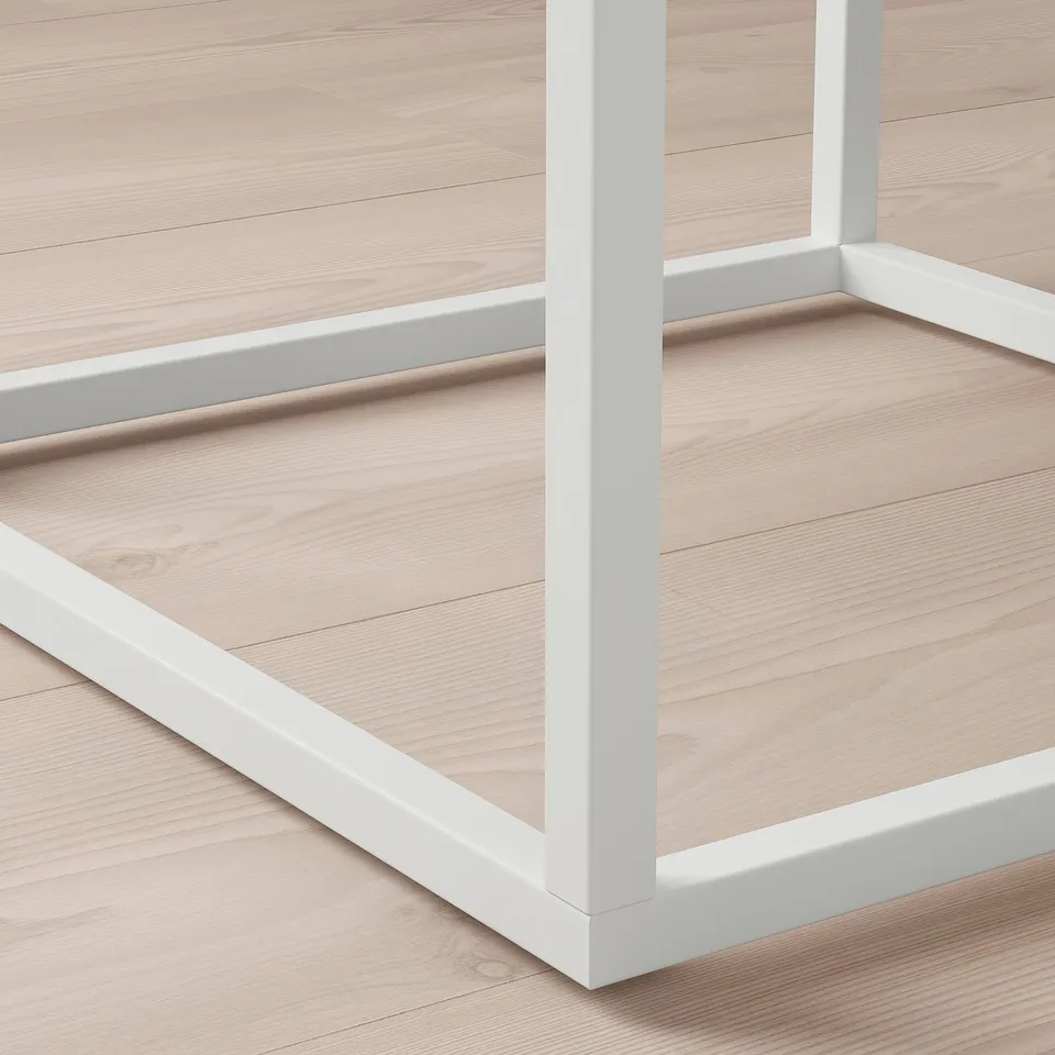 White metal bed frame corner detail; light wood floor.