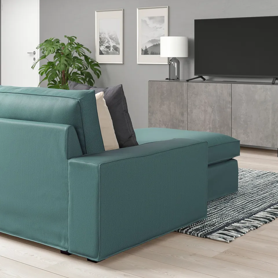 Modern living room with teal KIVIK sofa, sleek grey tv console, and rug. Sofa low armrests, deep seat cushions, and machine-washable fabric.
