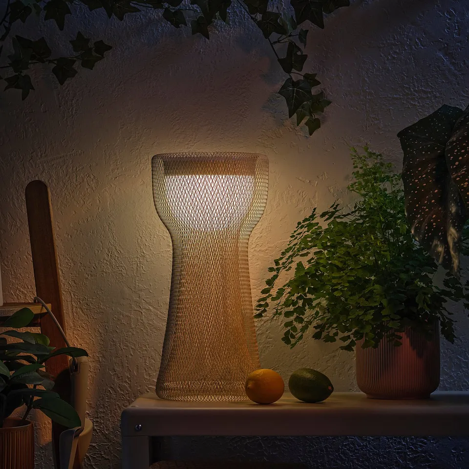 A decorative lamp on a shelf with fruits and plants, emitting a warm glow.