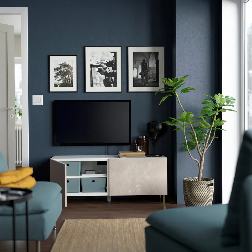 Modern living room with BESTÅ tv unit, blue velvet chairs, yellow blanket & plant.