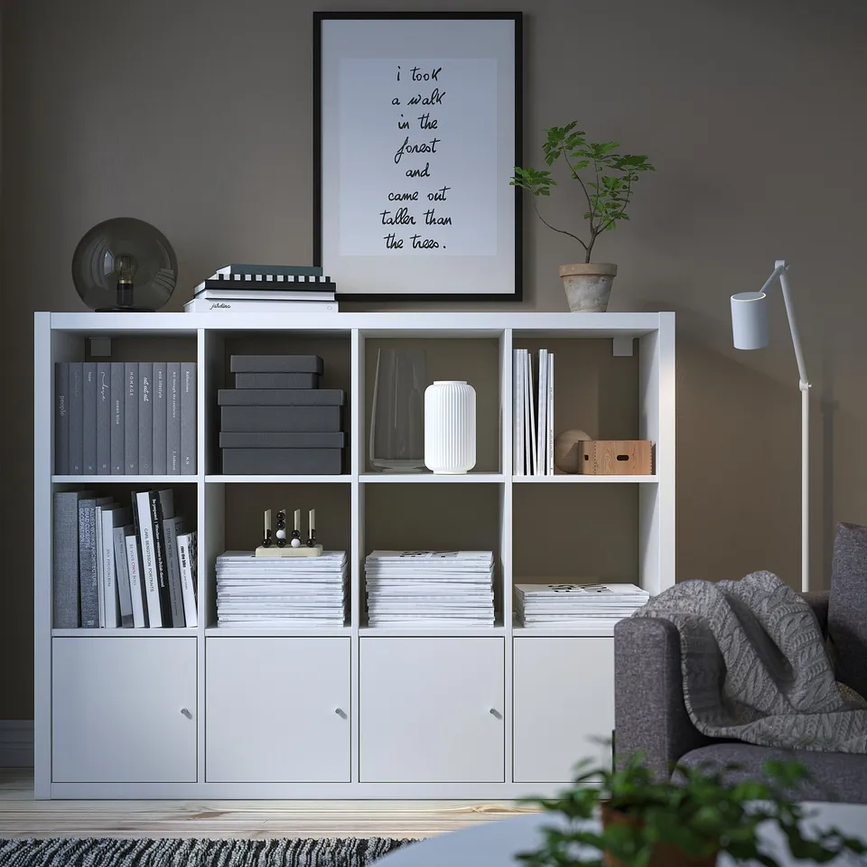 Modern living room with KALLAX bookshelf, lamp, sofa, and plant.