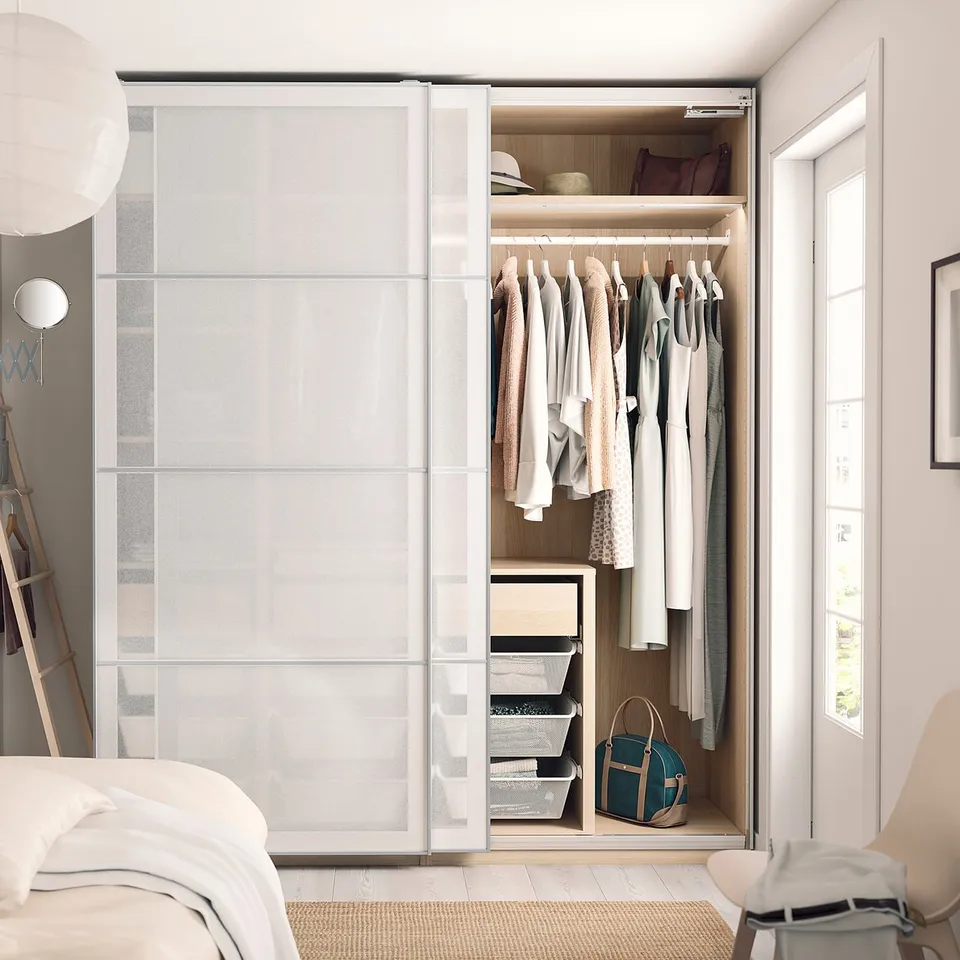 Modern bedroom a SVARTISDAL frosted glass wardrobe with sliding doors, neatly arranged clothes, hanging bags, and a cosy bed.