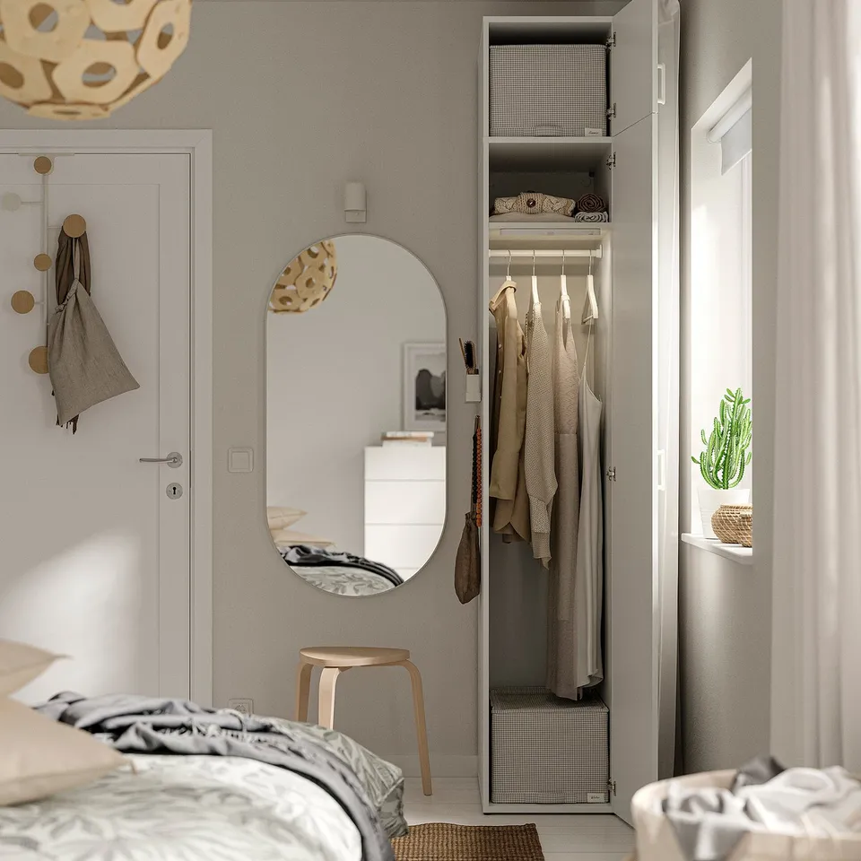 Bedroom with open closet showing clothes, mirror, and bed with blankets.