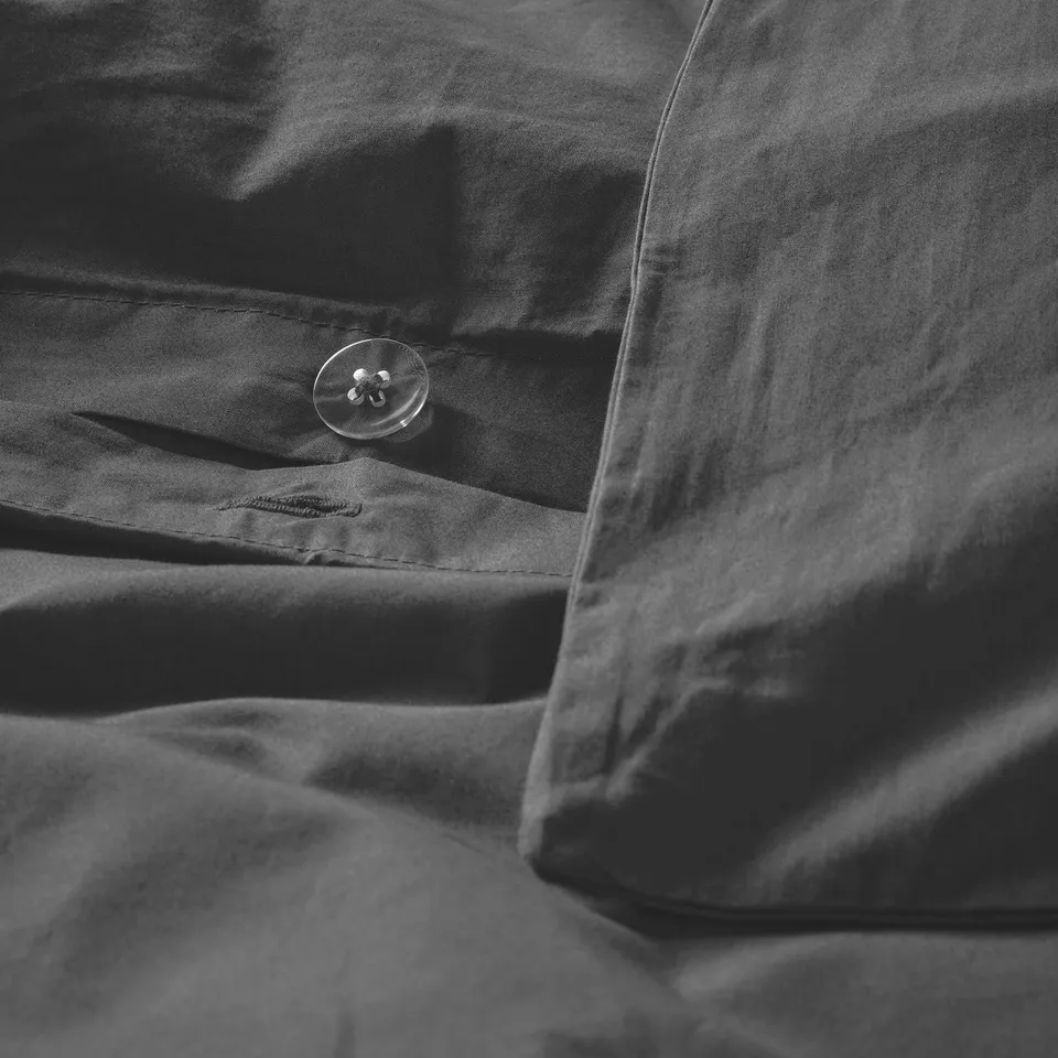 Close-up of dark grey duvet with crisp, textured fabric and visible button.