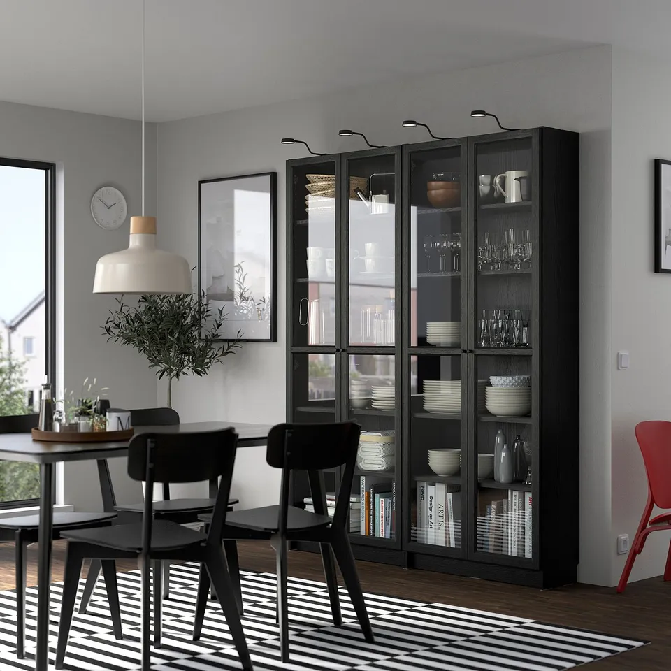 Black BILLY bookcase in dining room with dishes, books, and modern decor.