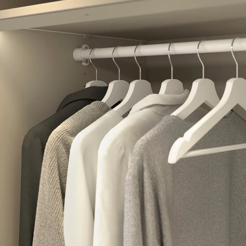 Wardrobe with sweaters on hangers.
