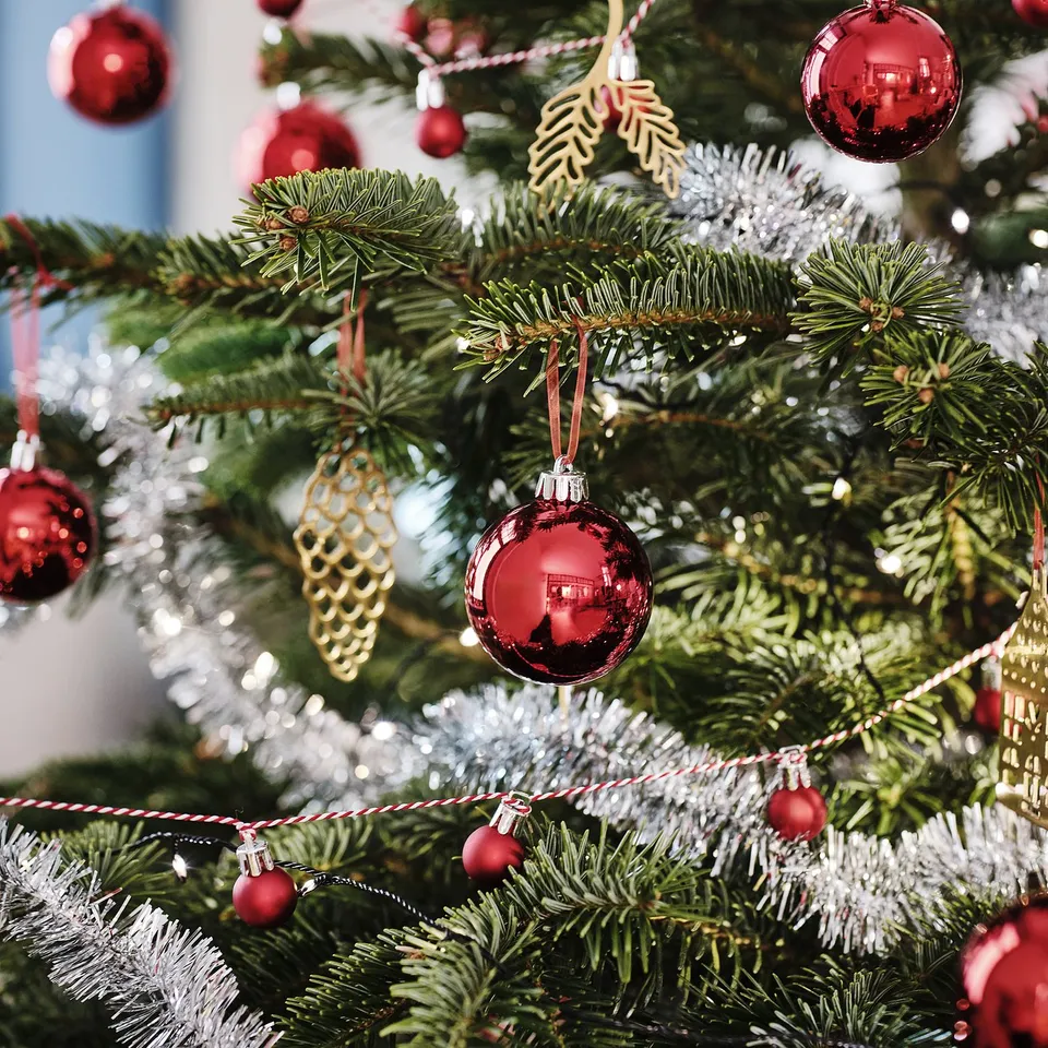 Christmas tree with red ornaments and golden pine cones.