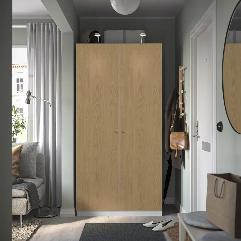A modern entrance a tall, light brown PAX wardrobe, matching the rooms minimalist design.