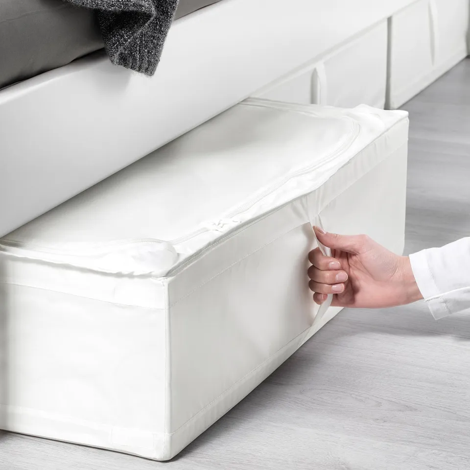 Hand opening rectangular white SKUBB storage case under bed, showcasing its handle for easy access.