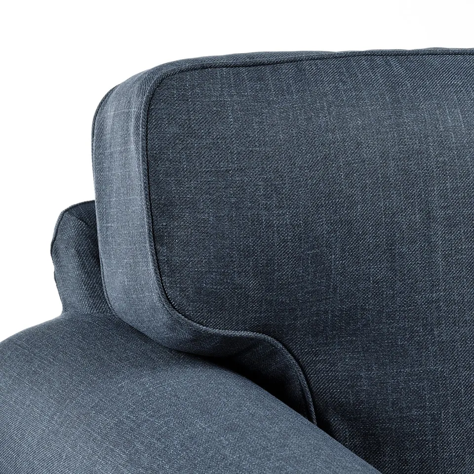 Dark grey upholstered sofa corner, showcasing plush cushions and fine stitching.