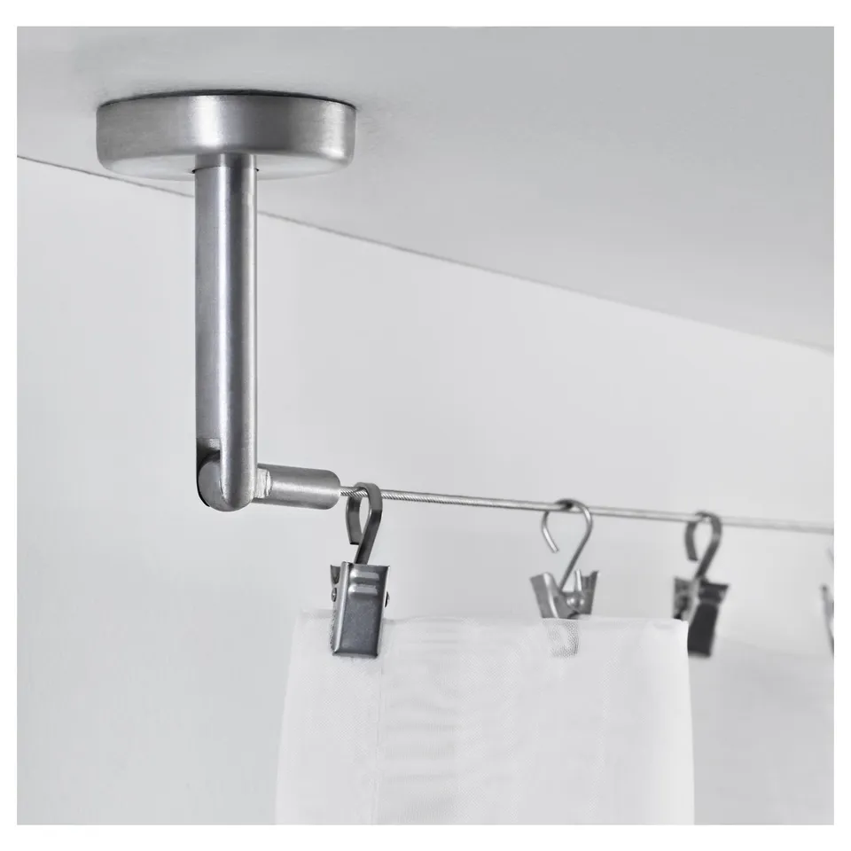 Silver ceiling-mounted curtain rod with clips holding white curtains. Shows part of DIGNITET curtain system.