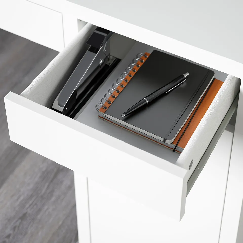 Open desk drawer revealing notebook, pen, and tech accessories in organised manner.
