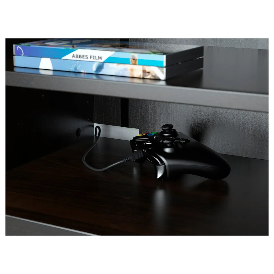 Black game controller on wooden tv stand with cable management.