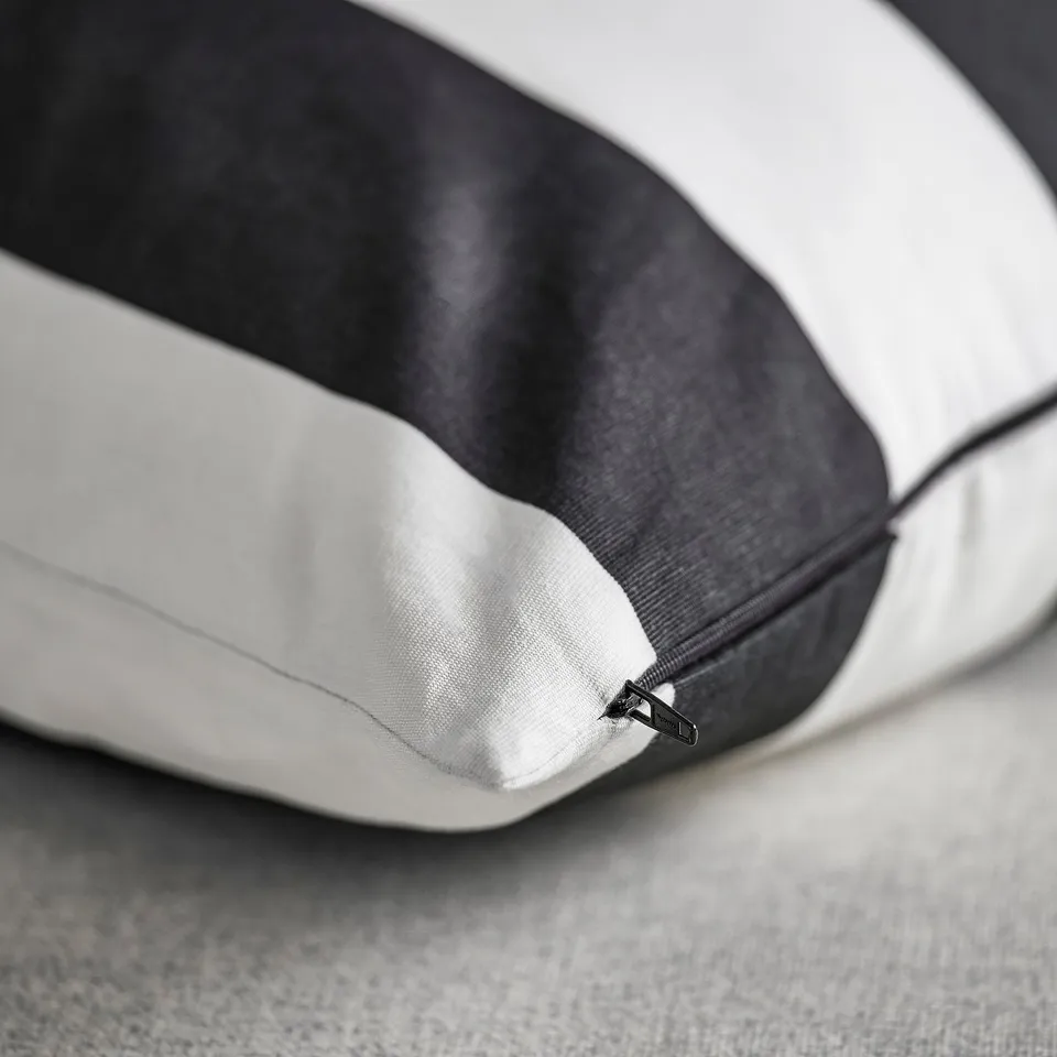Close-up of a cushion cover with black and white stripes, featuring a hidden zip closure.