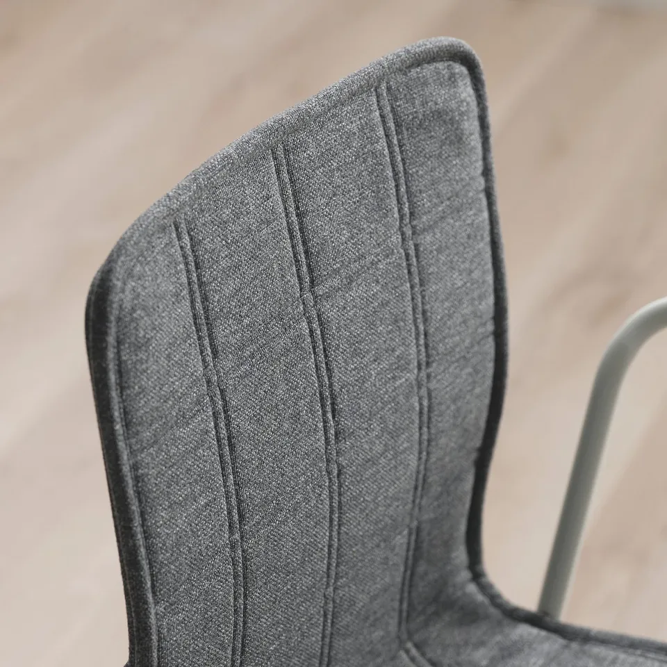 Close-up of a modern, sleek chair with grey, textured fabric, showcasing quality stitching and design.