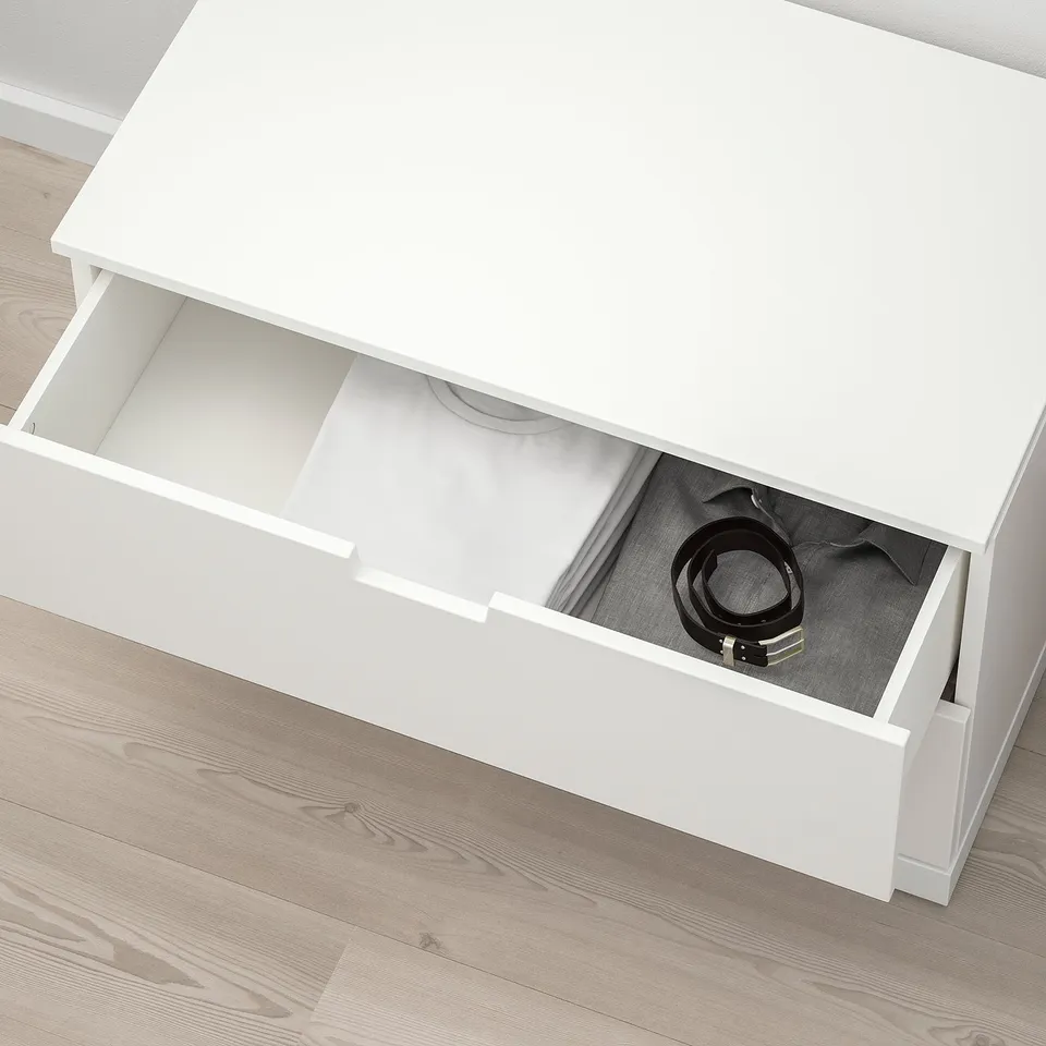 Open white NORDLI dresser with open drawer revealing belt inside, showcasing storage space.
