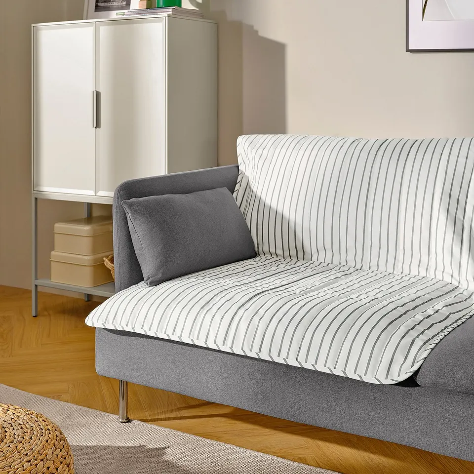 Modern living room with striped pet blanket on grey sofa.