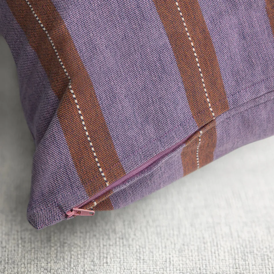 A striped pillowcase with zip closure, showcasing pink and orange stripes with blue base, handwoven with intricate patterns.