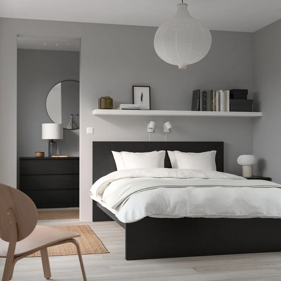Modern bedroom with MALM bed, white bedding, pendant light, bookshelf, chair, dresser & mirror.