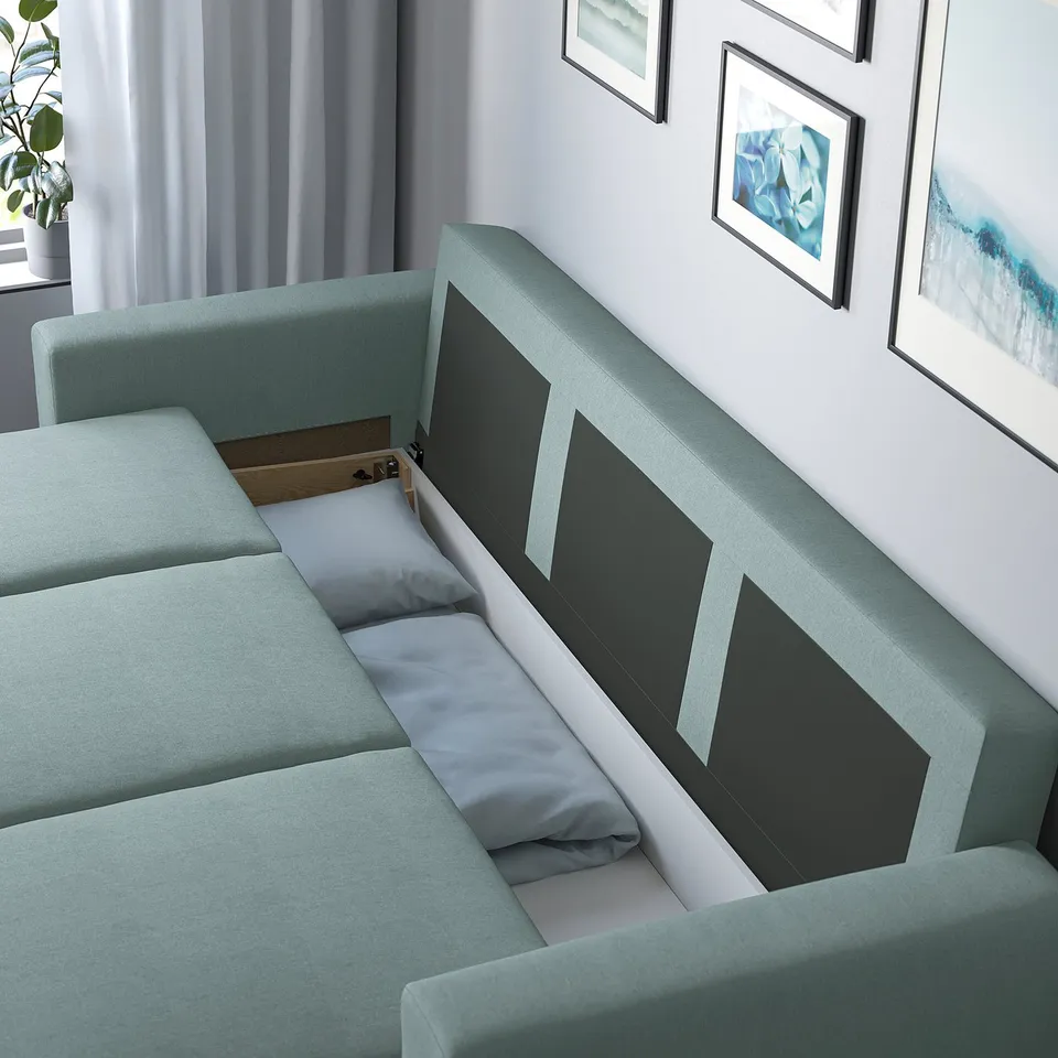 A turquoise sofa-bed with cushions and storage open underneath, revealed backrest, in a room with art and plants.