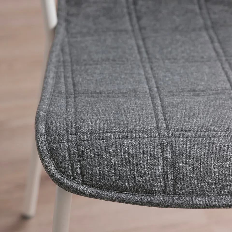 Close-up of soft, grey upholstered chair seat, showcasing textured fabric and neat stitching.