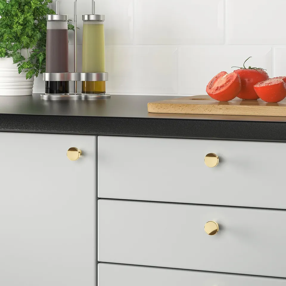 Modern kitchen with grey cabinets and gold knobs, featuring a tomato and herb display.