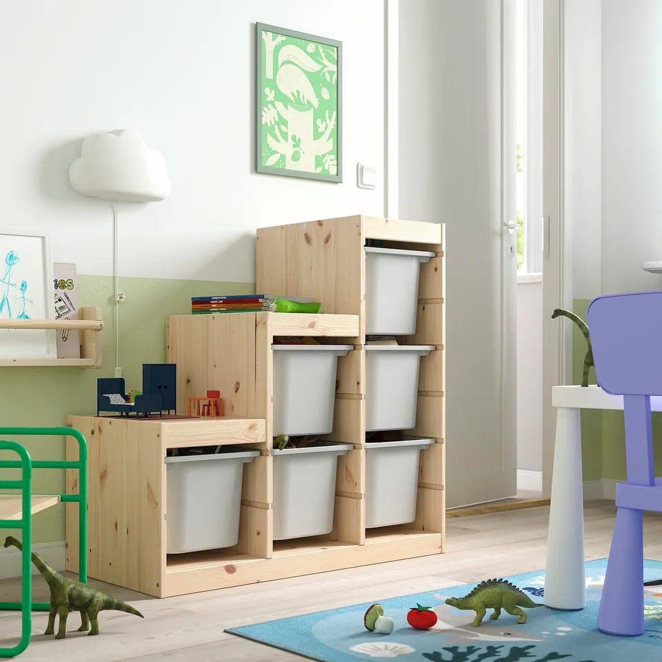 Childs room with light wooden TROFAST storage, white bins, green and blue decor, dinosaur toys, and a blue chair.