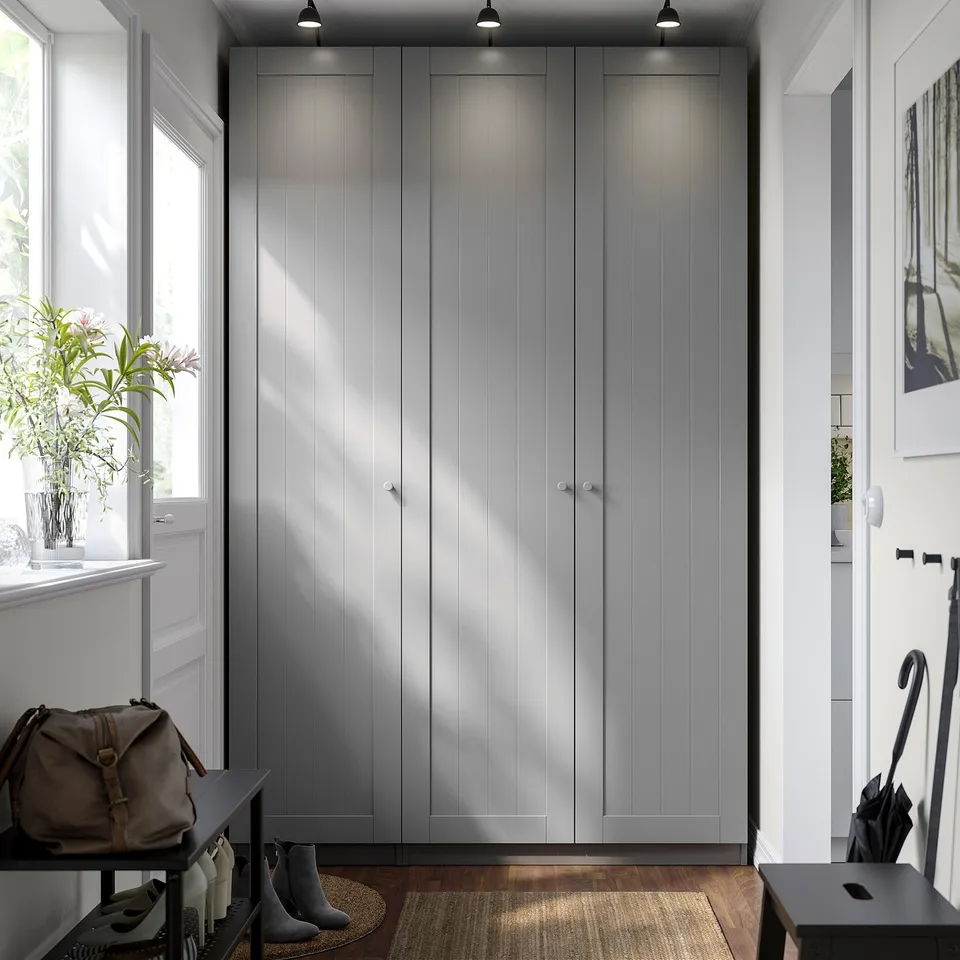 Modern grey PAX wardrobe with silver handles, built-in lights, and surrounding accessories.