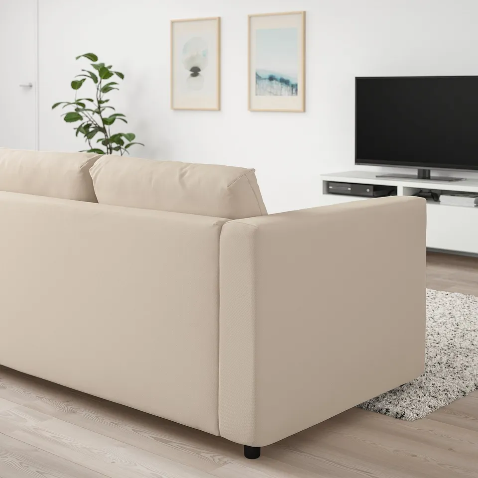 Modern living room: beige VIMLE sofa, black tv, white walls, plant, rug.