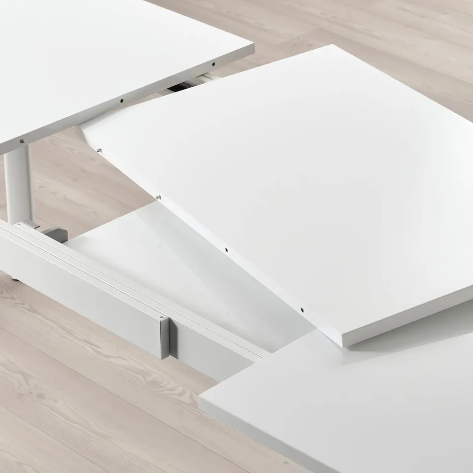 A white extendable dining table with two self-storing leaves inserted. The leaves extend the table surface, while the metal frame ensures stability.