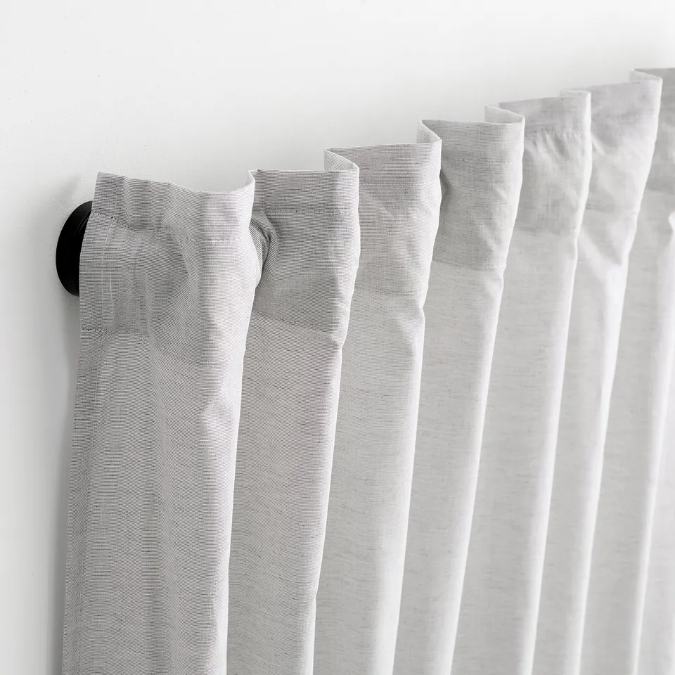 Black curtain rod with powder coating, holding sheer curtains, two wall fittings visible on left and right ends.