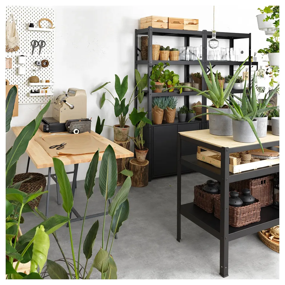 Black BROR storage system with shelves, baskets, plants, and a wooden tabletop. Modern and functional design.
