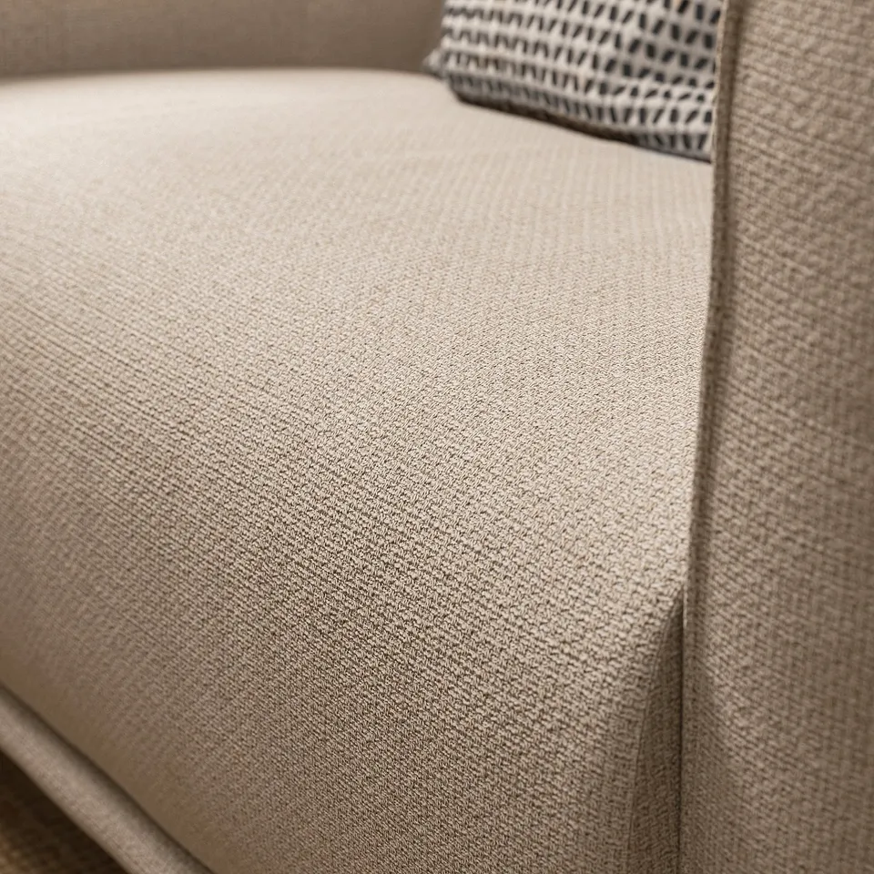 Soft, beige fabric armchair, deep seat, rounded shapes, inviting design.