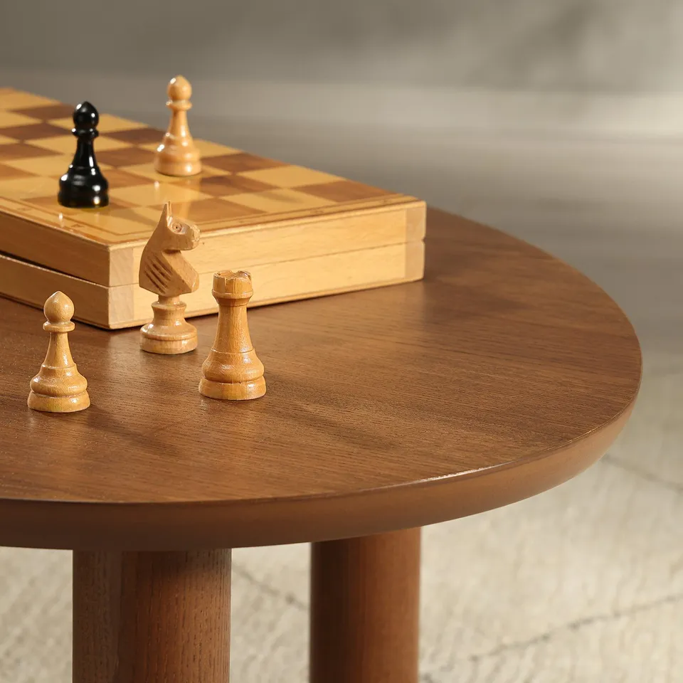 Chess pieces on wooden table: light and dark wood pawns, rooks, and knight on shiny, round table top.