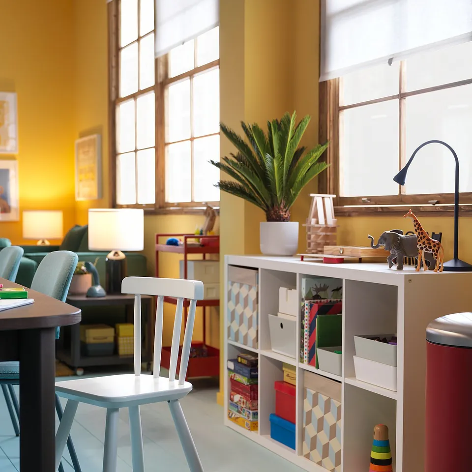 Bright, colourful kids room with a white junior chair, various toys, and a large window.