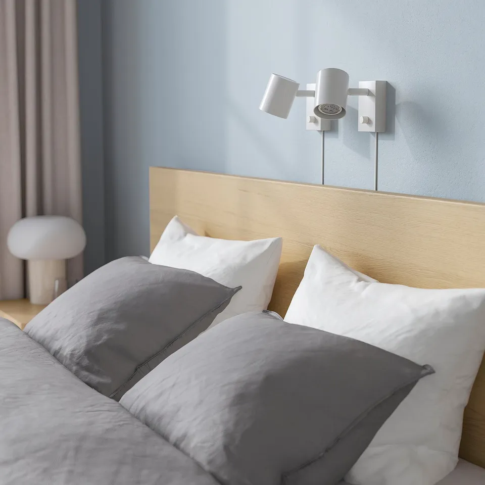 Wooden MALM bed with high headboard, adjustable sides, and wall lights. Grey and white bedding.