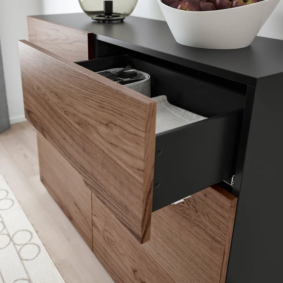 Modern oak veneer sideboard with open drawer revealing cutlery tray; black interior and top shelf holding fruit bowl.