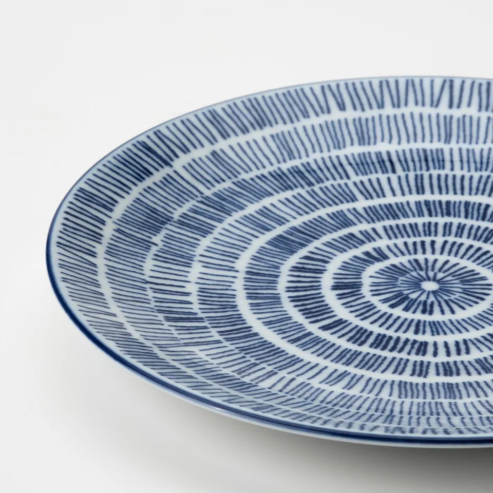 Blue and white patterned porcelain plate with concentric stripes. High-quality craftsmanship, detailed design.