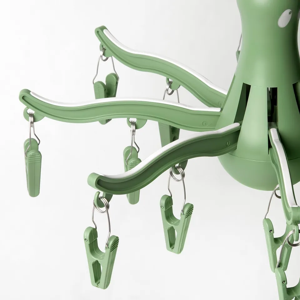 Green plastic sock dryer with 16 pegs, hooked and ready for use.