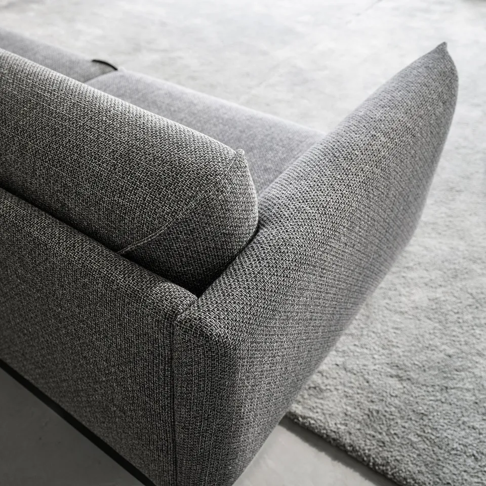 Modern sofas armrest and seat, upholstered in grey fabric, showcasing sleek design.