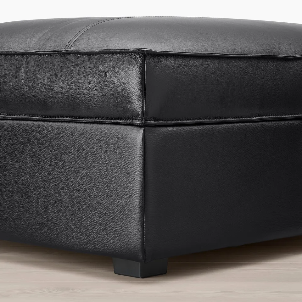 Close-up of KIVIK footstool in dark leather, showcasing smooth upholstery and sturdy construction.